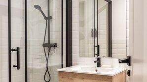 Une salle de bain moderne avec une douche à parois de verre, un meuble-lavabo en bois et un miroir.