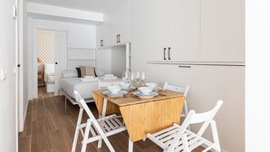 Une pièce moderne et minimaliste, dotée d’un coin repas avec une table en bois et des chaises blanches.