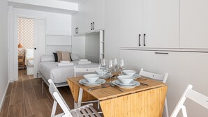 Une chambre moderne et minimaliste comprenant un coin repas, un lit et un dressing.