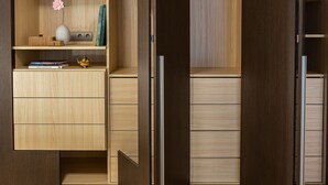 Habitación con armario empotrado, un escritorio pequeño con un florero y libros, y suelo de madera.