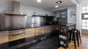 Cocina moderna con electrodomésticos de acero inoxidable, pared de ladrillo decorativa y piso de baldosas negras.