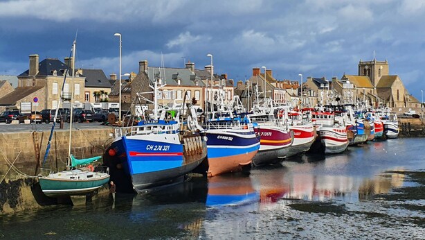 A harbor with multiple boats docked along the waterfront, surrounded by buildings and a clear sky. - Le Gîte de la Grange de Dîme. Gite Tout Confort à 1 km du Phare de Gatteville (Gatteville-le-Phare)