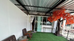 Un espace extérieur aménagé avec une pelouse artificielle verte, deux canapés en cuir marron et une petite table.