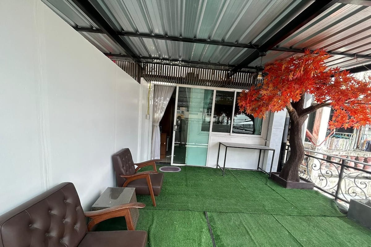 Un espace extérieur aménagé avec une pelouse artificielle verte, deux canapés en cuir marron et une petite table.