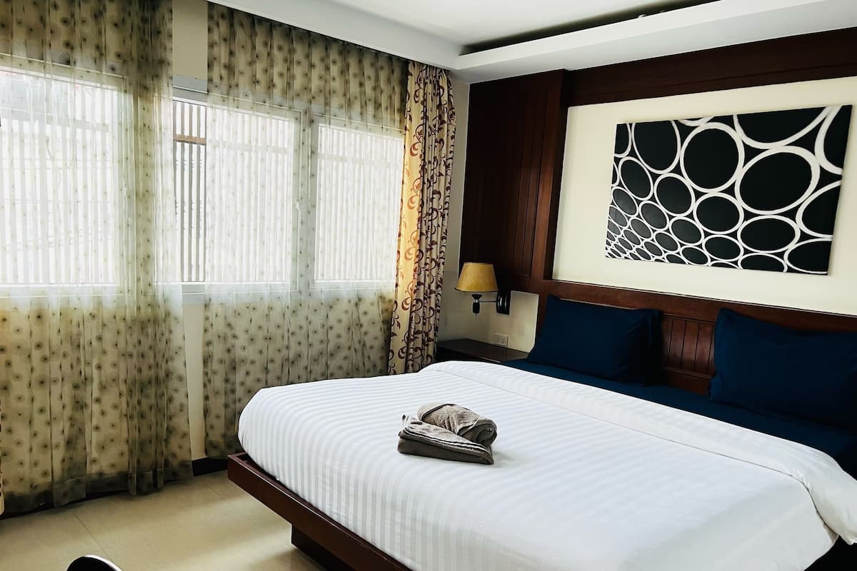 Une chambre d’hôtel avec un grand lit, une table de chevet avec une lampe et une œuvre d’art accrochée au mur.