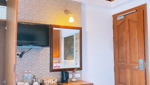 Une pièce avec un plafond en bois, un bureau avec une télévision, un réfrigérateur et une chaise.