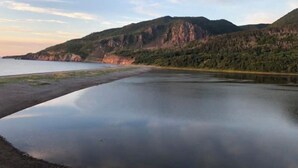 A calm lake with a mountainous backdrop and a clear sky. - The Riverside Windchaser!  (Petit Étang)