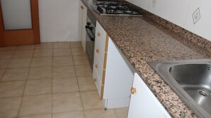A kitchen with a granite countertop, stainless steel sink, and a gas stove. - Jardín II, 5º Solo Familias (Xeraco Playa)