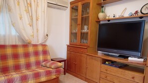 A living room with a sofa, wooden cabinet, and a flat-screen TV.