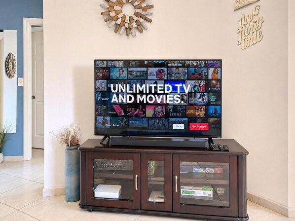 Televisor de pantalla plana sobre un mueble de madera con la pantalla mostrando 'UNLIMITED TV AND MOVIES'.