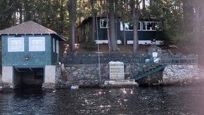 A cabin with a dock extending into a body of water, surrounded by trees.