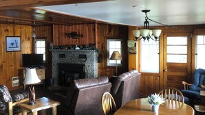 A cabin interior with a fireplace, wooden furniture, and a stone wall.