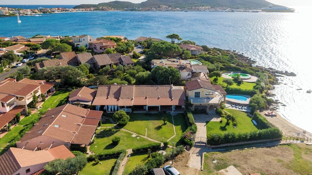 A coastal residential area with houses, a swimming pool, and a view of the sea.
