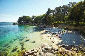 A beach with clear turquoise water, rocky shoreline, and people sunbathing. - Maison Bretonne Typique Plage des Oiseaux à Fouesnant Beg Meil (Fouesnant)
