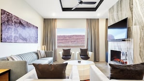 A modern living room with a sofa, armchairs, a coffee table, a flat-screen TV, and a fireplace.