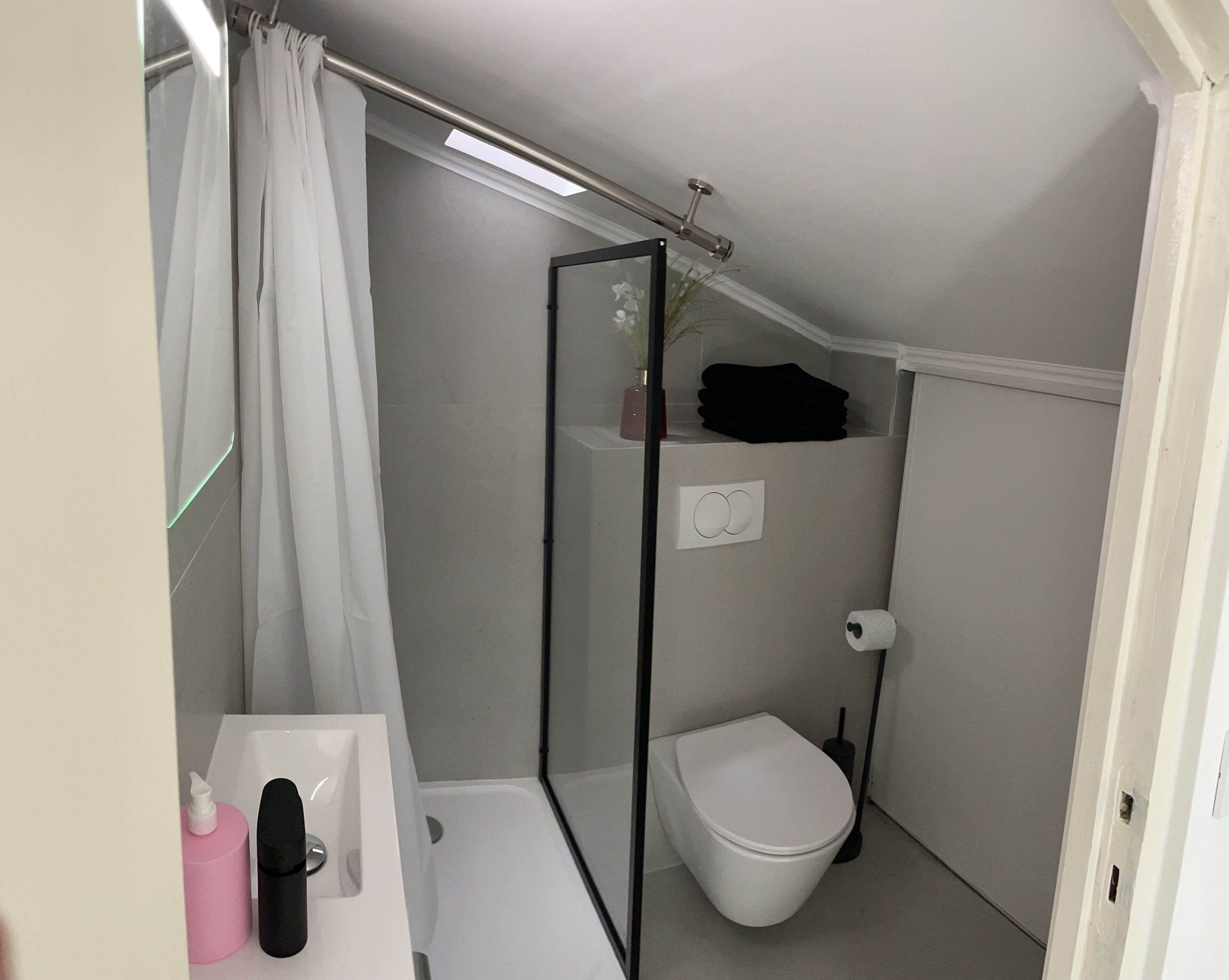 A small, compact bathroom with a shower, toilet, and sink.