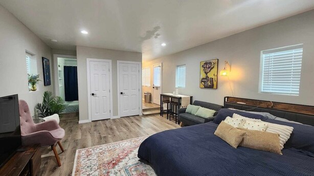 Une chambre spacieuse avec un grand lit, un canapé et un bureau. Deux portes donnent accès à d’autres pièces.