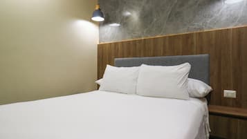 Una cama bien hecha con sábanas blancas en una habitación con paneles de madera y una pared de mármol.