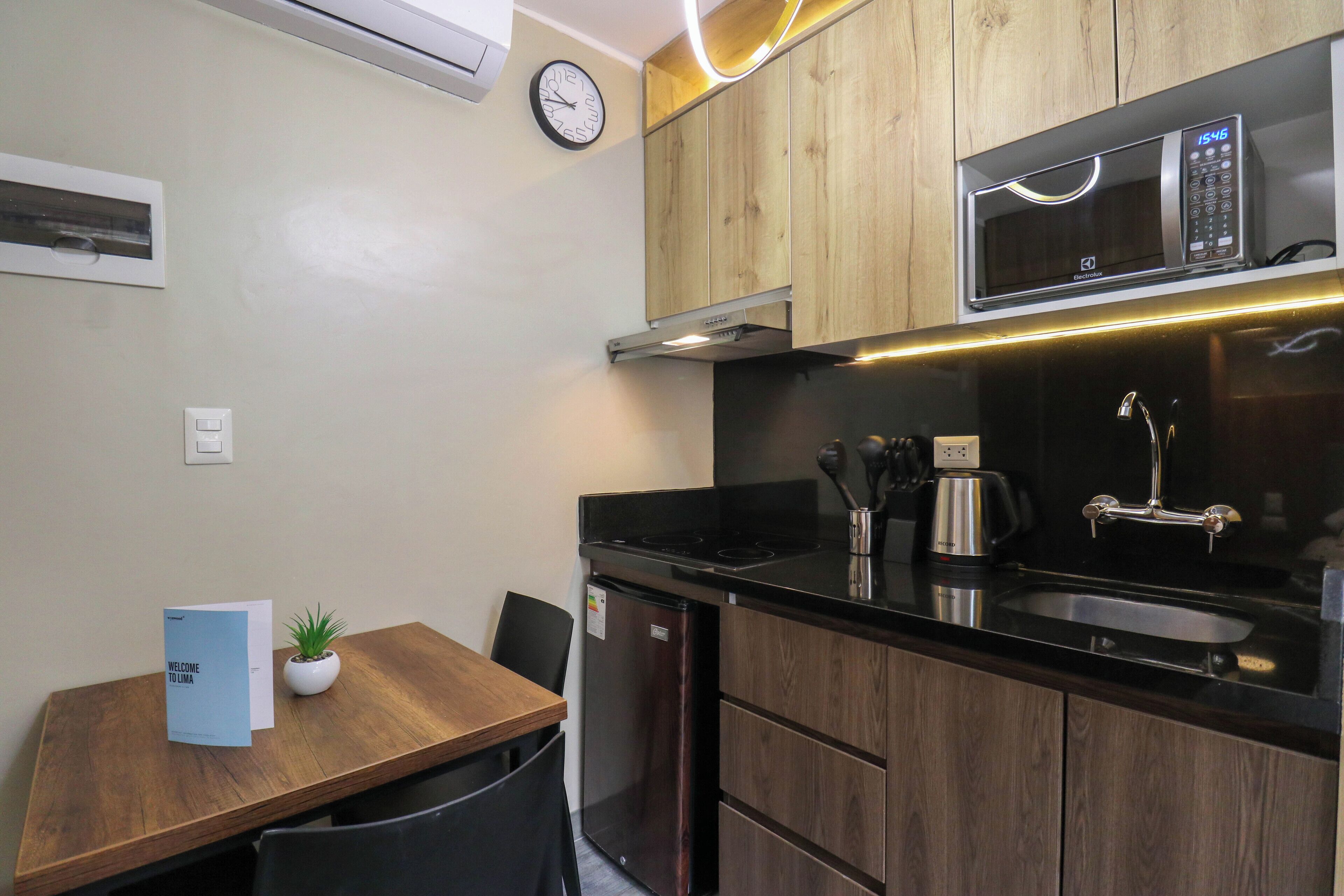 A compact kitchen with a microwave, sink, and a small refrigerator.