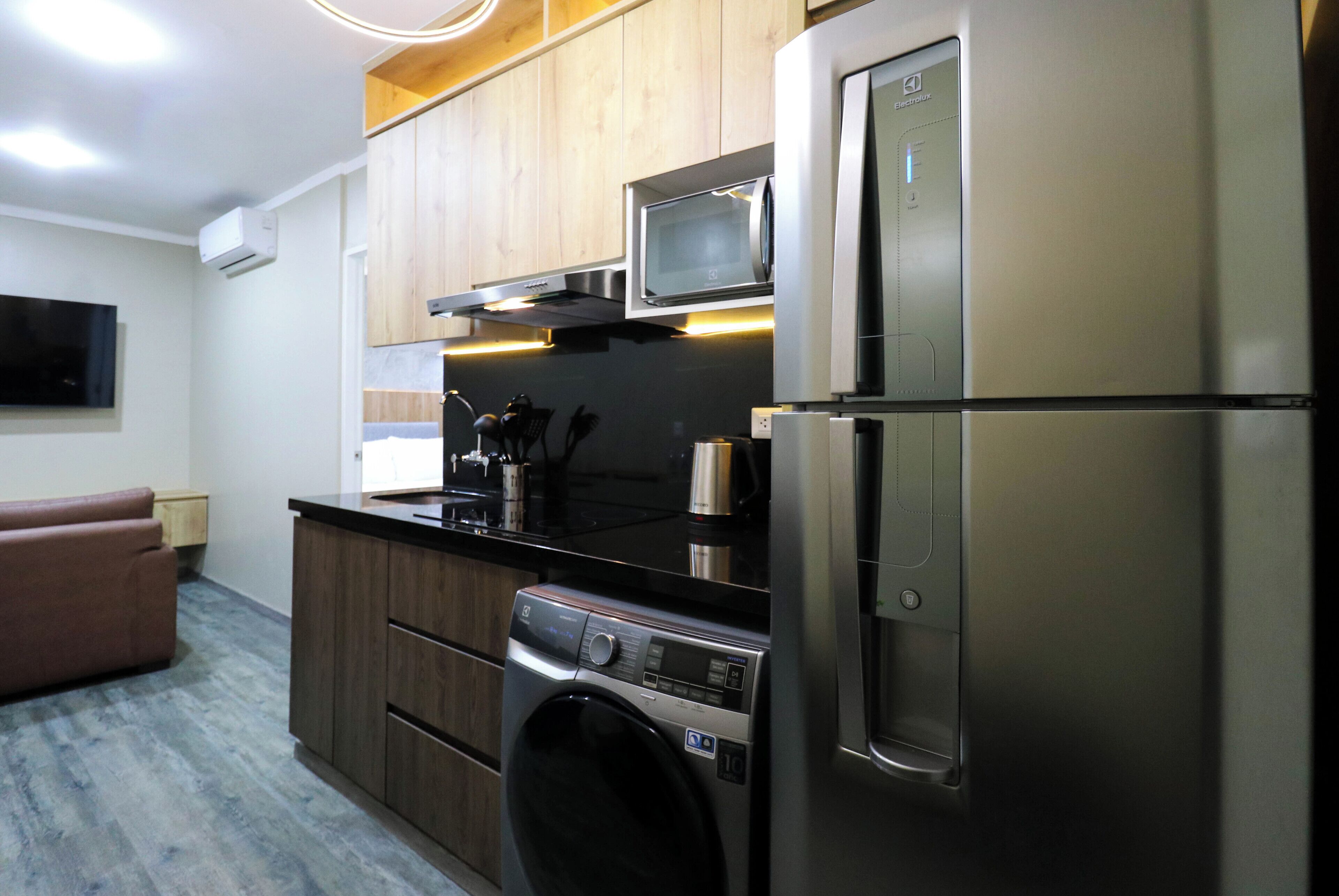 A modern kitchen with stainless steel appliances, wooden cabinets, and a built-in microwave.