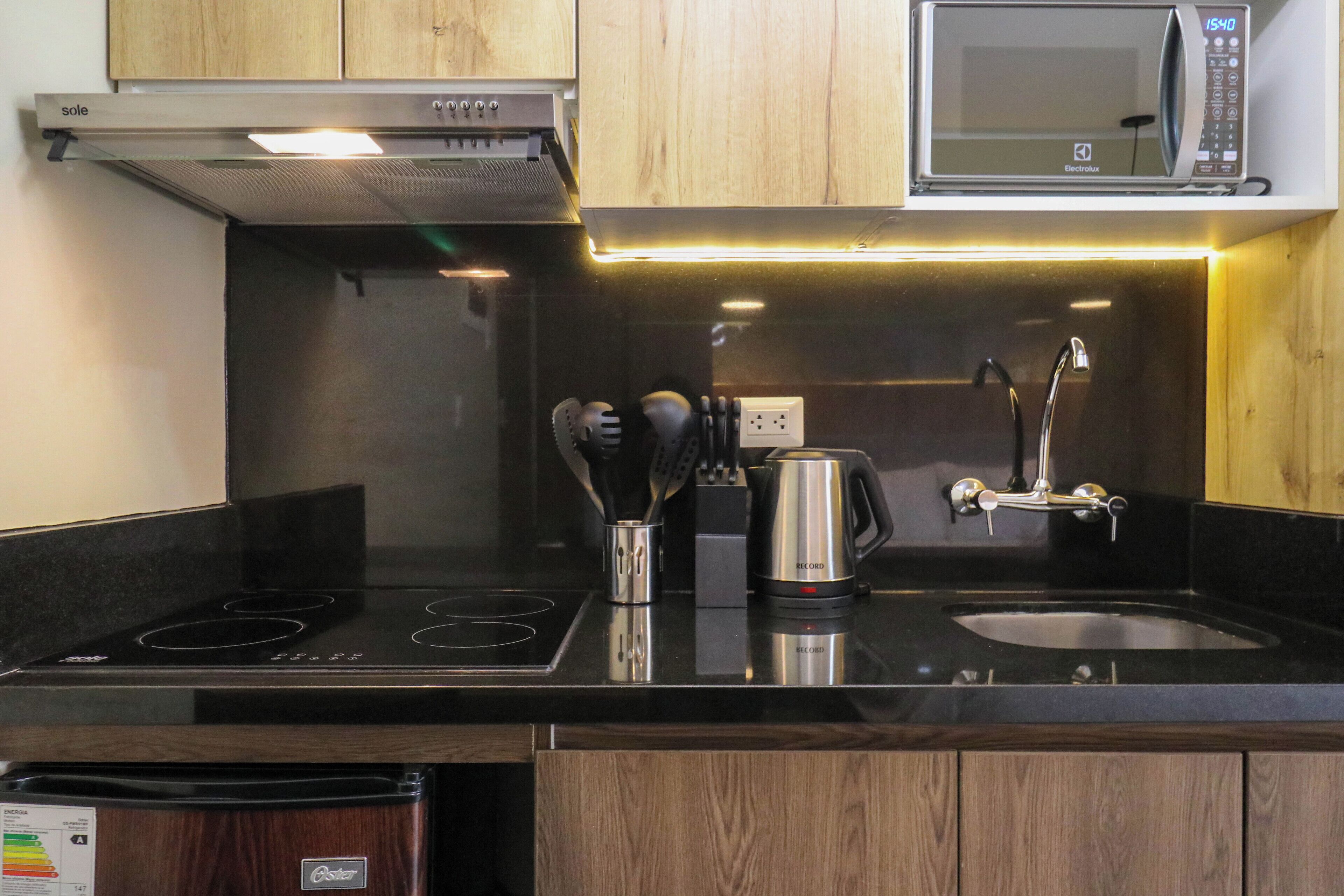 A modern kitchen with a black countertop, stainless steel appliances, and wooden cabinets.