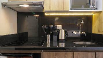 A modern kitchen with a black countertop, stainless steel appliances, and wooden cabinets.