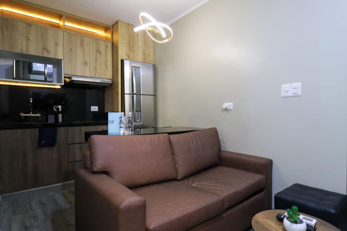 A modern kitchen with wooden cabinets, a stainless steel refrigerator, and a built-in microwave.
