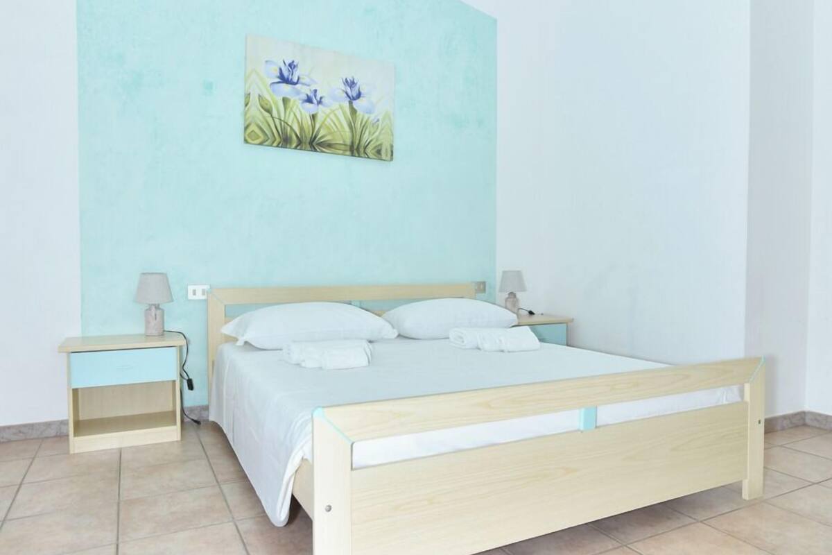 A bedroom with a bed, two bedside tables, and a wall-mounted painting.