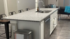 A modern kitchen with a granite countertop, stainless steel appliances, and a built-in dishwasher.