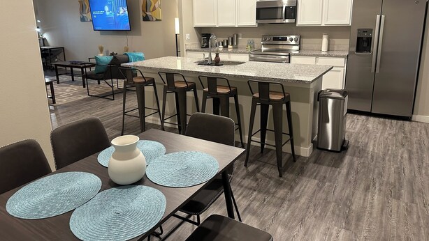 A modern kitchen with white cabinets, stainless steel appliances, and a central island with bar stools.