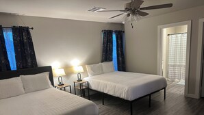 A hotel room with two beds, a ceiling fan, and a bathroom with a shower curtain.