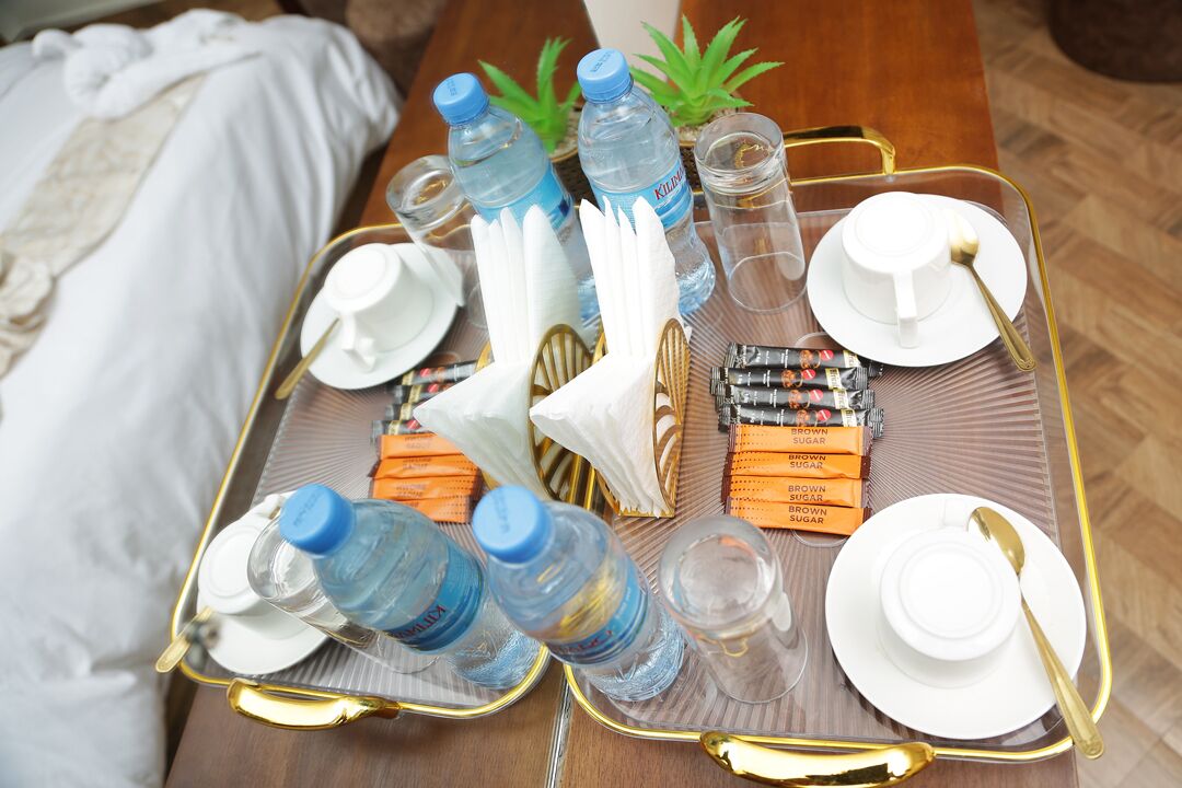 A tray with water bottles, plates, cutlery, and snacks on a wooden table.