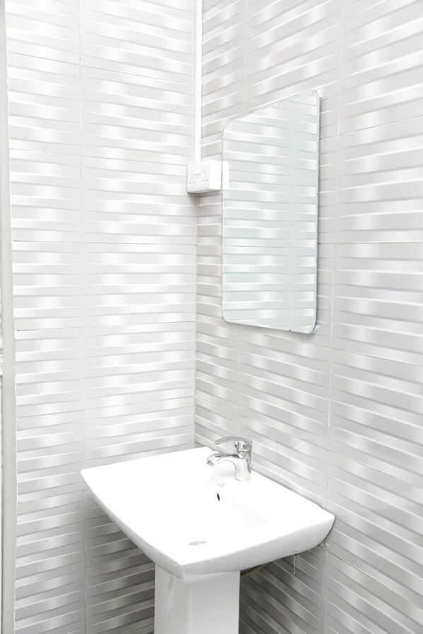 Un baño con un lavabo blanco, un espejo y una pared con textura.