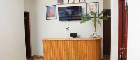 Un mostrador de recepción con un televisor de pantalla plana, diplomas enmarcados y una planta en maceta.