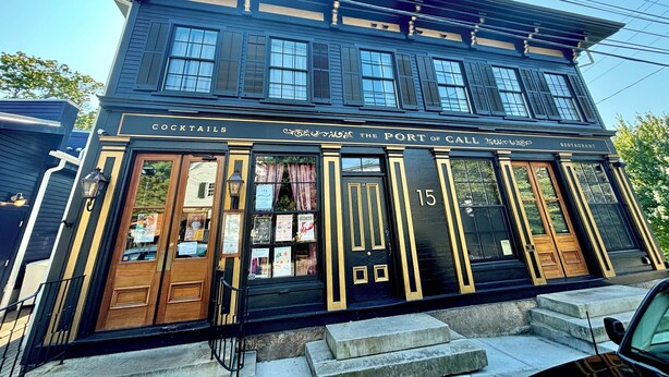 Un edifici negre amb un rètol que diu "Cocktails The Port of Call 2015 Restaurant" i el número "15" a la porta.