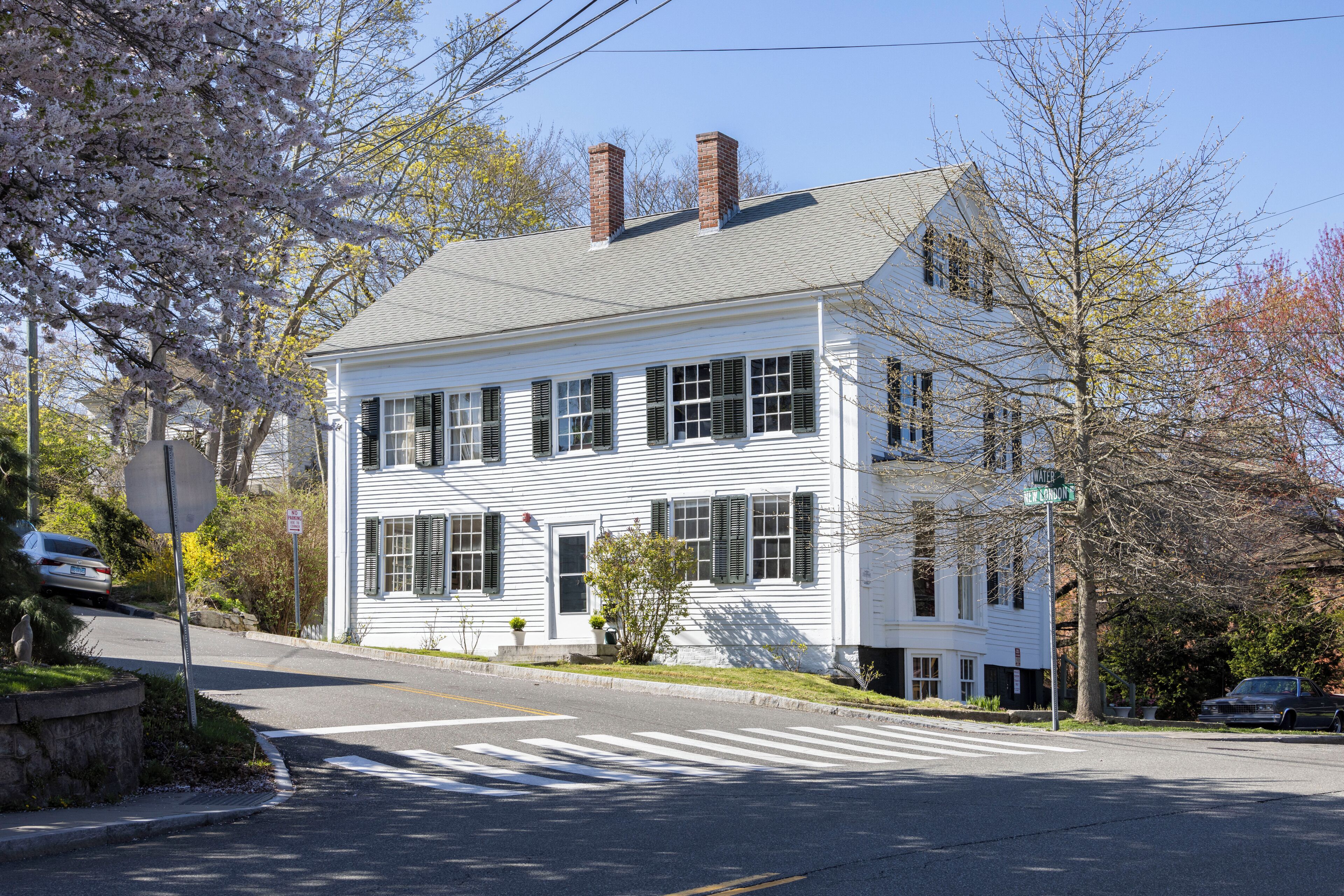 A two-story white house with a gabled roof and brick chimneys.