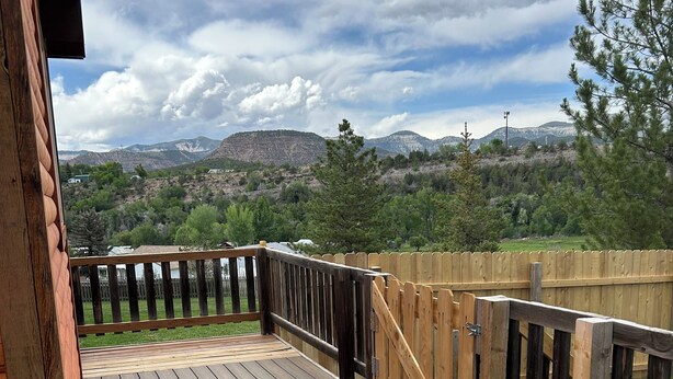 A wooden deck with a railing, overlooking a mountainous landscape. - One room guest house with hot tub, three twin beds, one futon, kitchen, bathroom (Collbran)