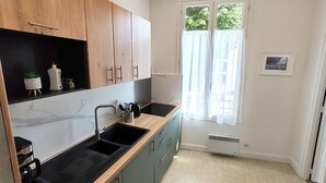 Una cocina moderna con armarios de madera, encimera negra y ventana con cortinas de gasa.