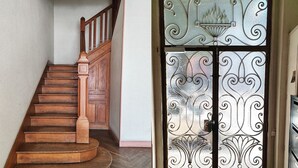 Una escalera de madera con barandilla y una puerta con detalles de metalería.