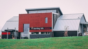 Un edificio moderno con una fachada roja llamativa y un letrero que dice 'burning kiln winery'.