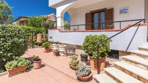 Un edificio bianco con un balcone, piante in vaso e una scala.