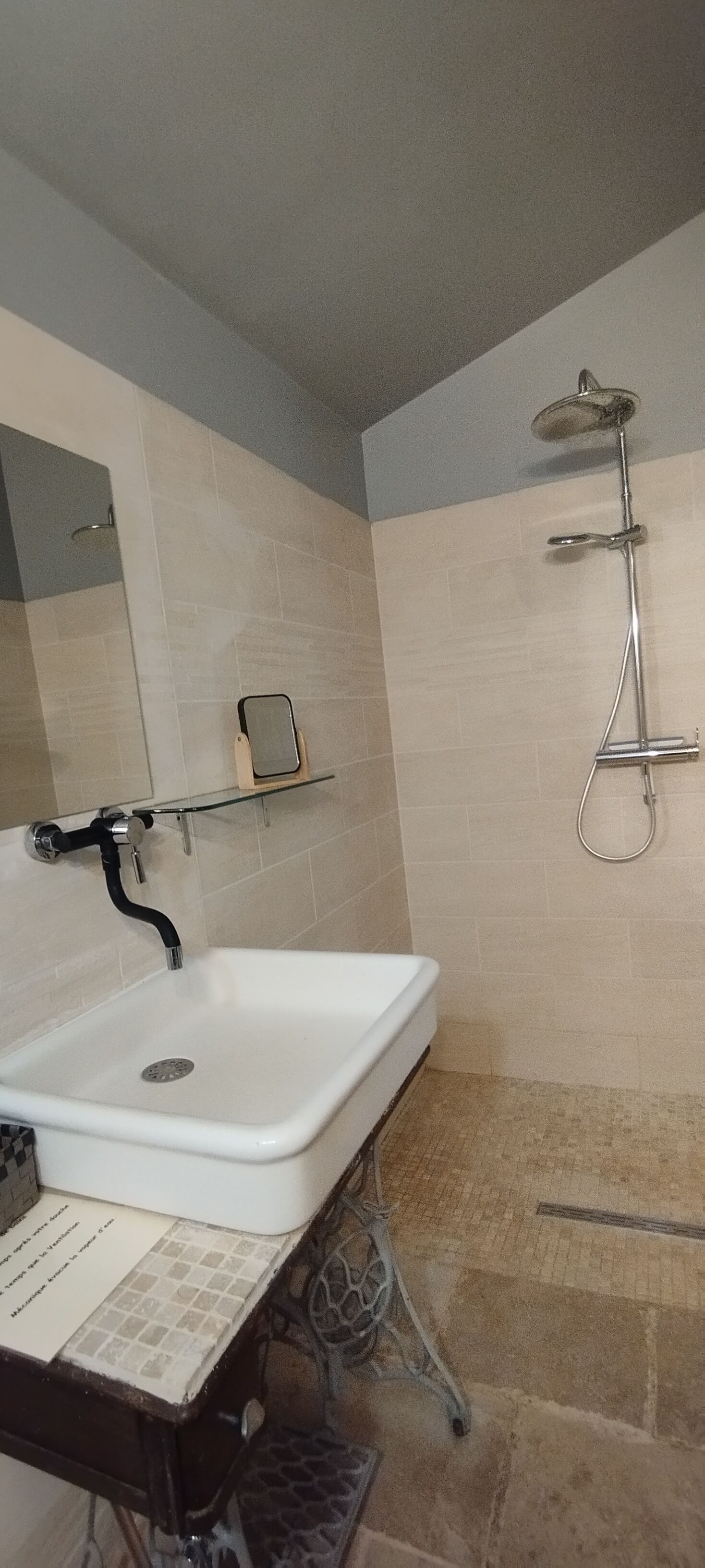 Ein Badezimmer mit einem weißen Waschbecken, einer Dusche und gefliesten Wänden.