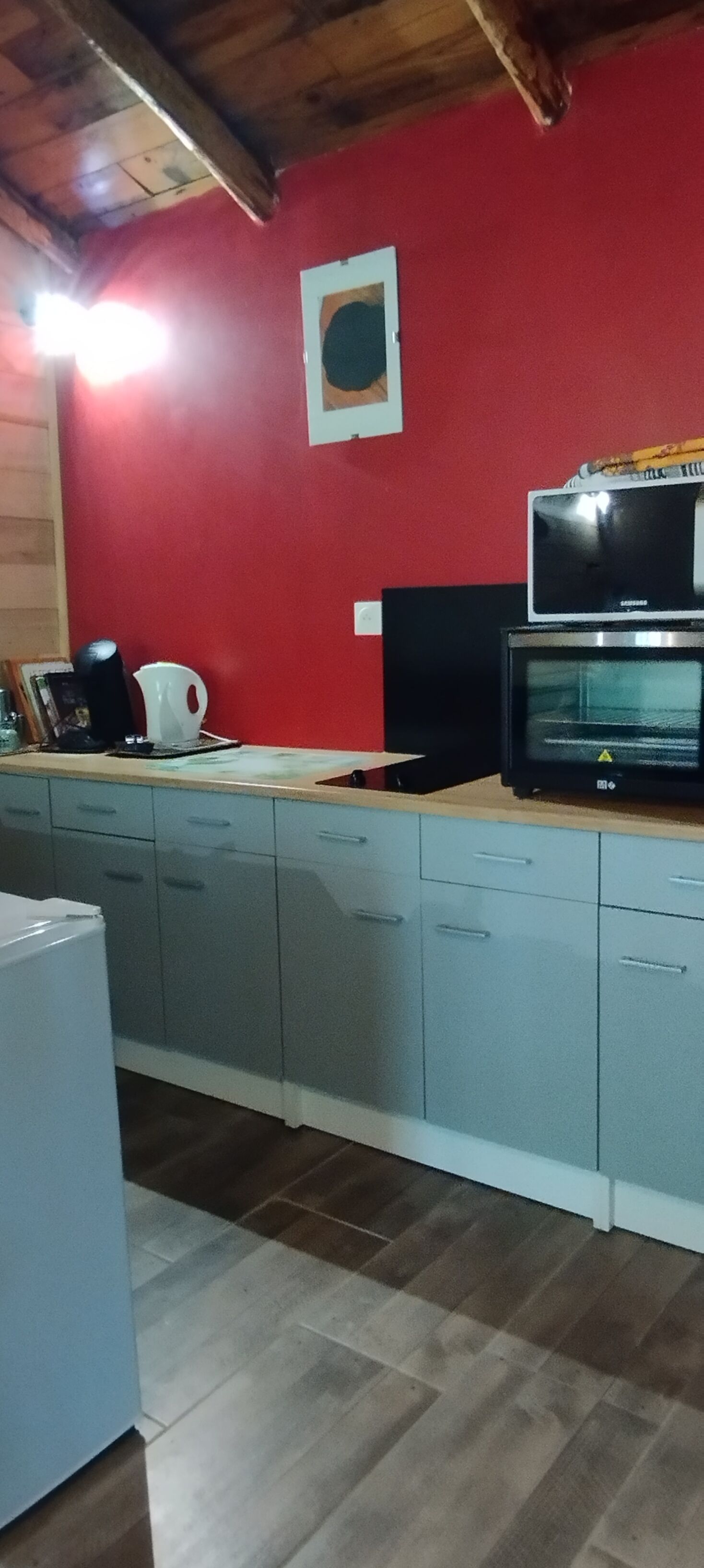 Una cocina con armarios grises, una pared roja y un microondas sobre la encimera.