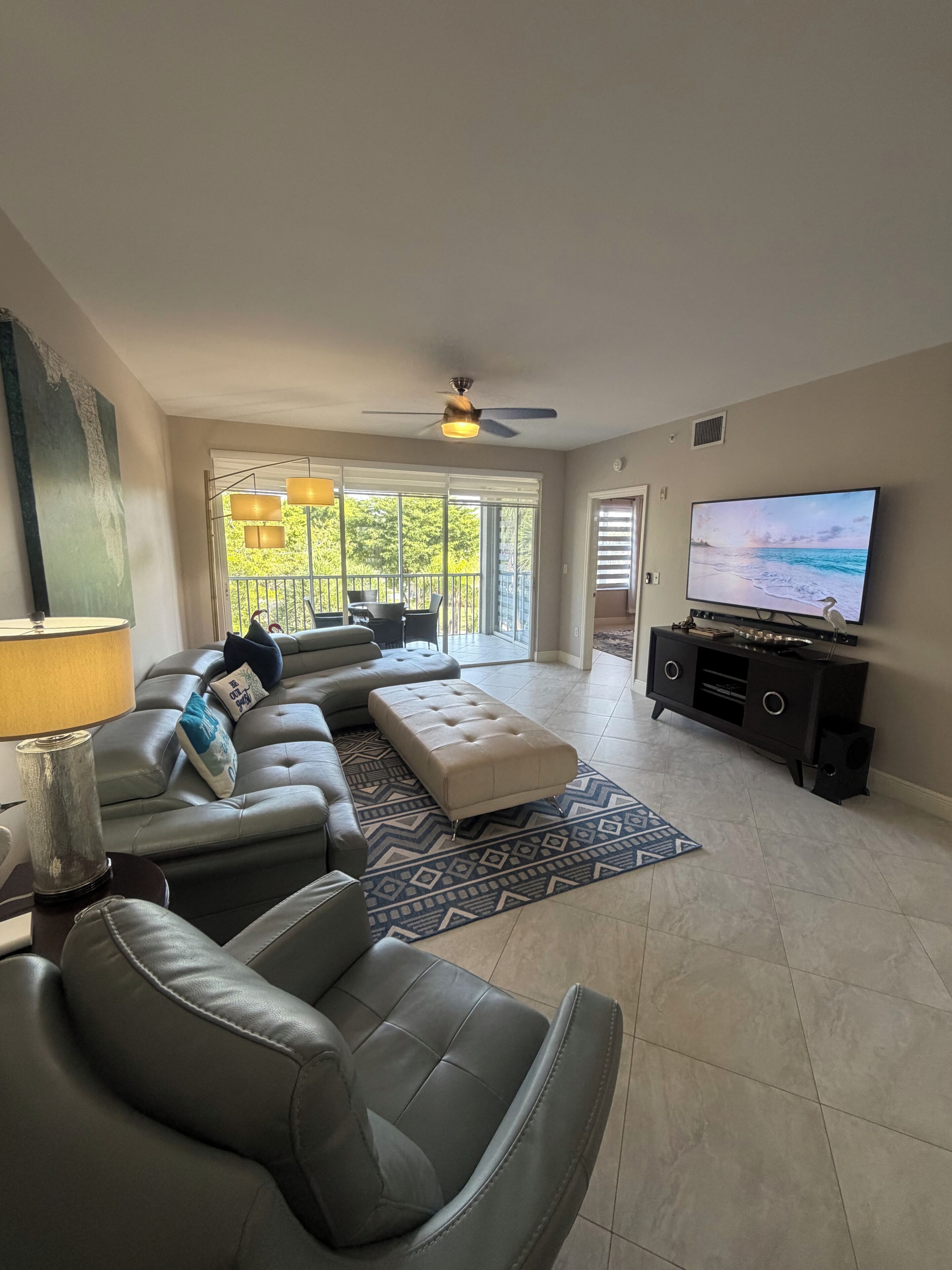 A modern living room with a sectional sofa, a television, and a ceiling fan.