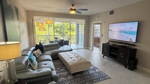A modern living room with a sectional sofa, a television, and a ceiling fan. - Perfect Getaway! Naples, Walk To Vanderbilt Beach -Immaculate! (Naples)