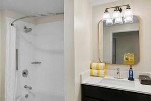 Une salle de bain avec une douche, un lavabo et un miroir avec éclairage.