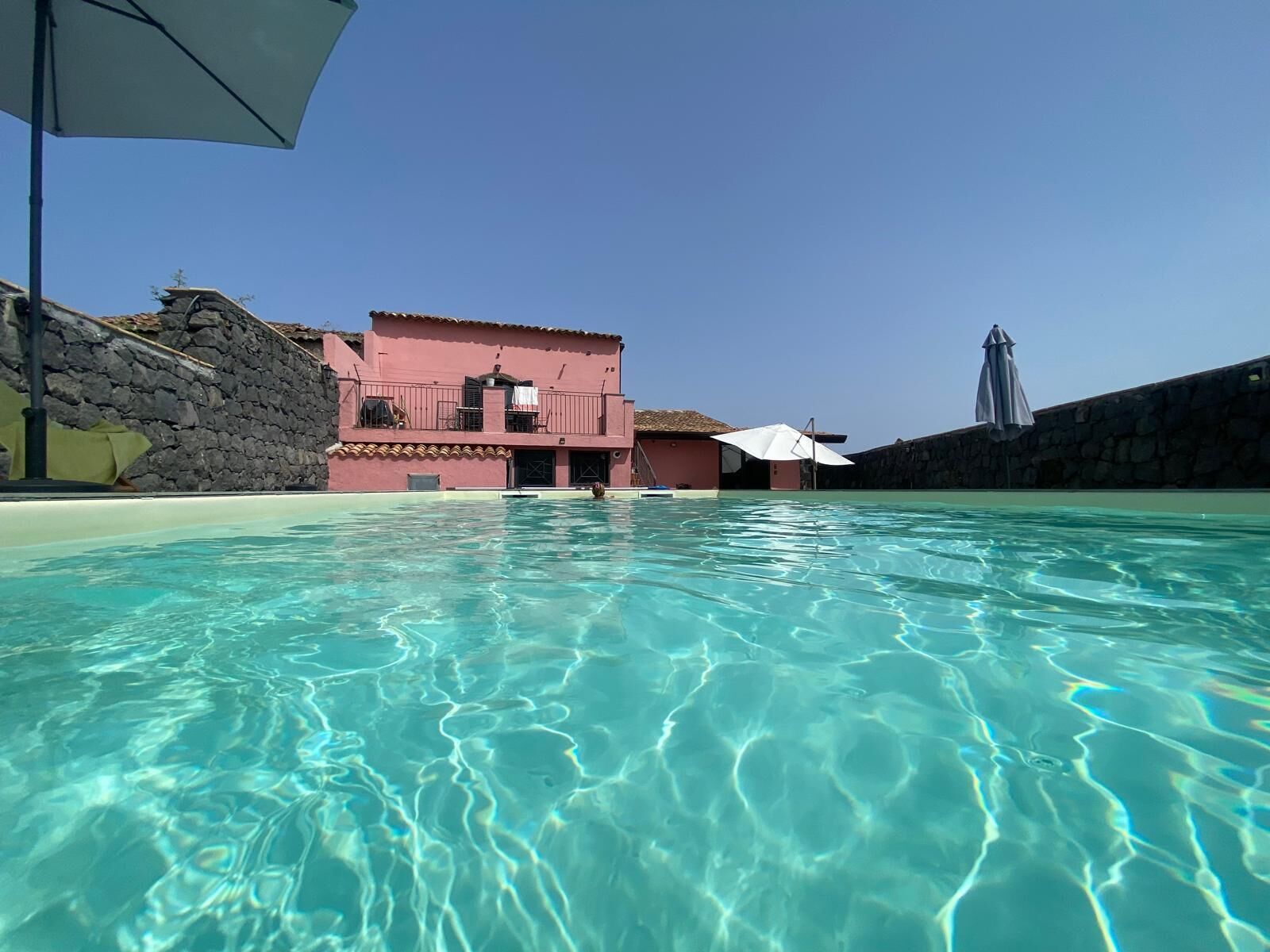 A clear swimming pool with a pink building in the background.
