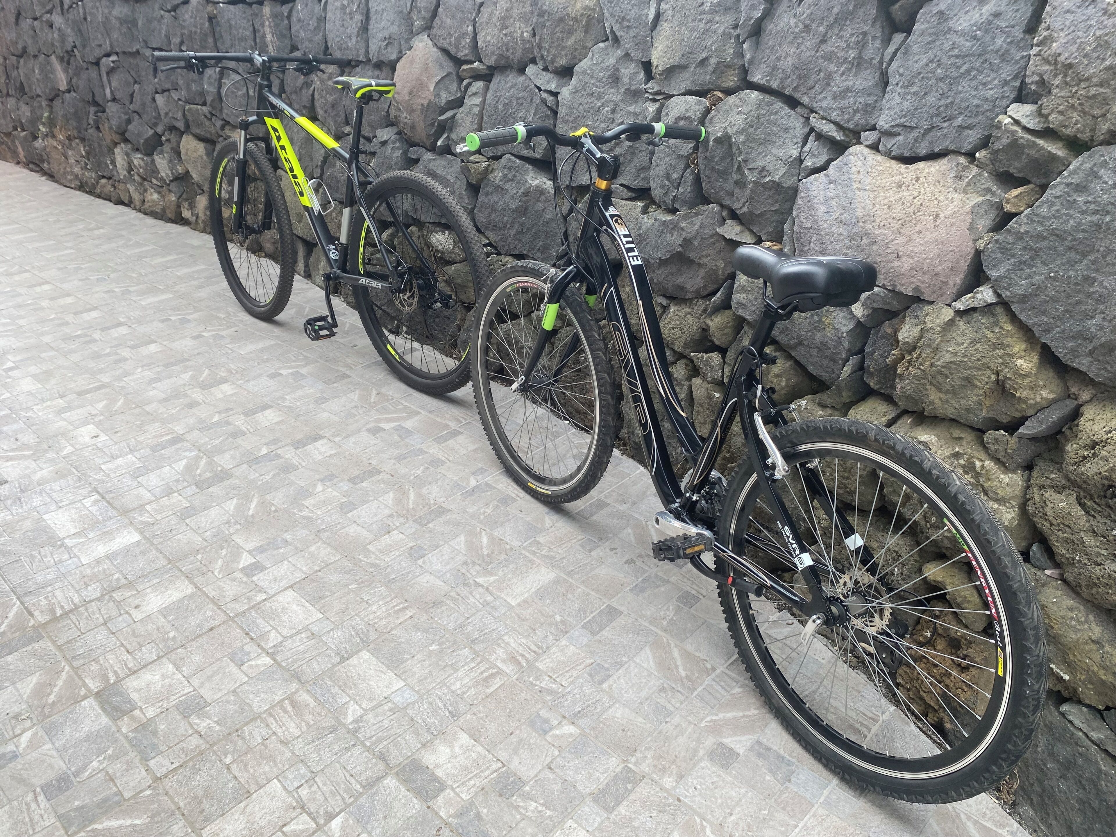 Dos bicicletas estacionadas junto a una pared de piedra.