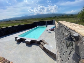Una piscina al aire libre, sombrillas, sillones reclinables de piscina