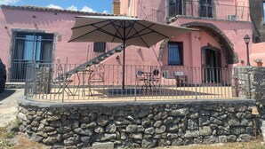 A pink building with a stone wall, a staircase, and outdoor furniture. - Le Decime Retreat (Mascali)